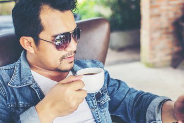 Café'de rahatlatıcı gülümseyen smartphone ile genç adam.