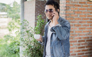 Café'de rahatlatıcı gülümseyen smartphone ile genç adam.