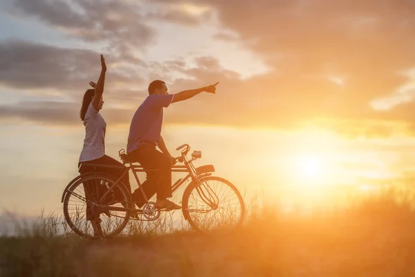 甜蜜的年轻夫妇的剪影在爱的快乐时光骑自行车 — 图库照片