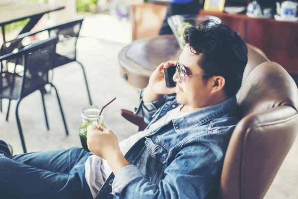 Café'de rahatlatıcı gülümseyen smartphone ile genç adam.