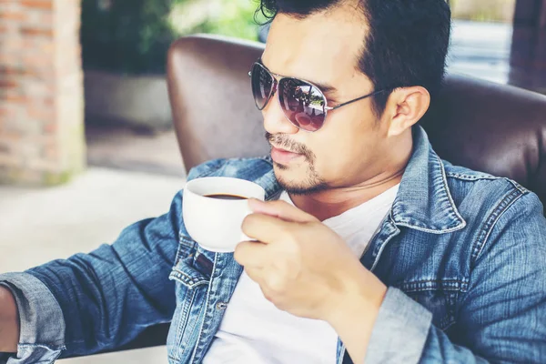 Café'de rahatlatıcı gülümseyen smartphone ile genç adam.