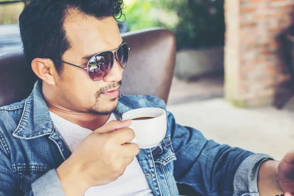 Café'de rahatlatıcı gülümseyen smartphone ile genç adam.