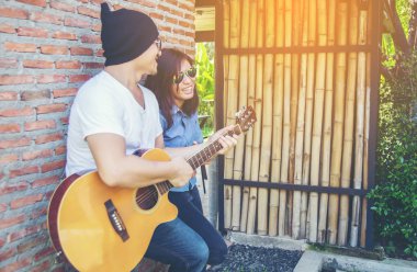 Genç hipster adam onun tatile rahatlatıcı için gitar çalmak zevk ile doğal ve taze hava.