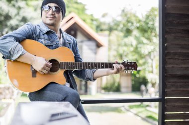 Genç hipster adam onun tatile rahatlatıcı için gitar çalmak zevk ile doğal ve taze hava.