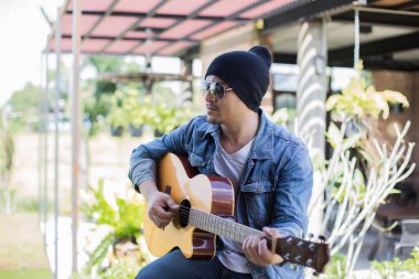 Genç hipster adam onun tatile rahatlatıcı için gitar çalmak zevk ile doğal ve taze hava.