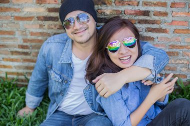 Kız arkadaşı için açık tuğla duvara gitar hipster adam birlikte zevk.