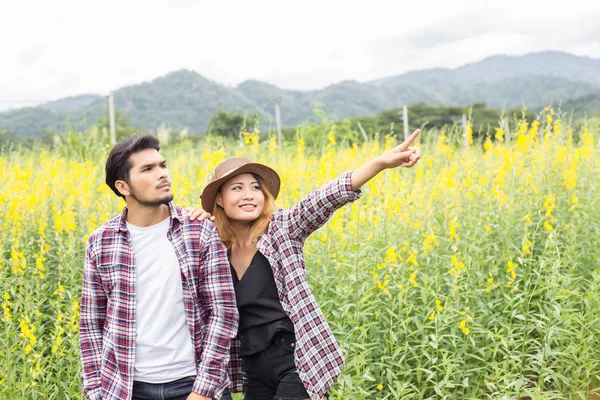 Genç hippi çift sarı çiçek alanında yaz rahatlatıcı. Doğa ile.