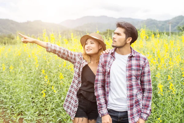 Genç hippi çift sarı çiçek alanında yaz rahatlatıcı. Doğa ile.