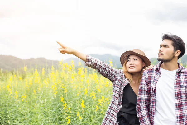 Genç hippi çift sarı çiçek alanında yaz rahatlatıcı. Doğa ile.