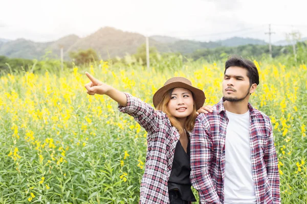 Genç hippi çift sarı çiçek alanında yaz rahatlatıcı. Doğa ile.