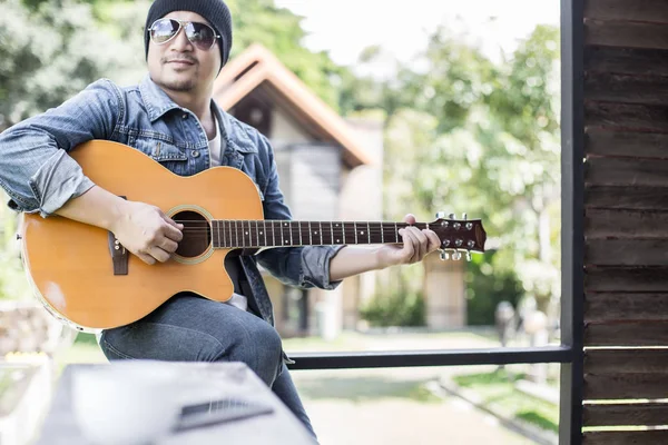 Genç hipster adam onun tatile rahatlatıcı için gitar çalmak zevk ile doğal ve taze hava.