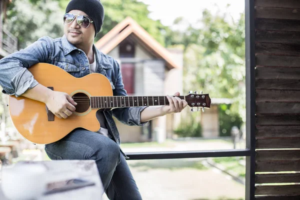 Genç hipster adam onun tatile rahatlatıcı için gitar çalmak zevk ile doğal ve taze hava.