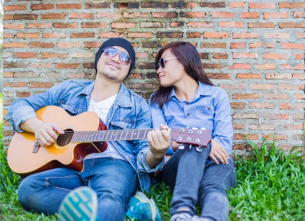 Kız arkadaşı için açık tuğla duvara gitar hipster adam birlikte zevk.
