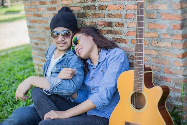 Kız arkadaşı için açık tuğla duvara gitar hipster adam birlikte zevk.