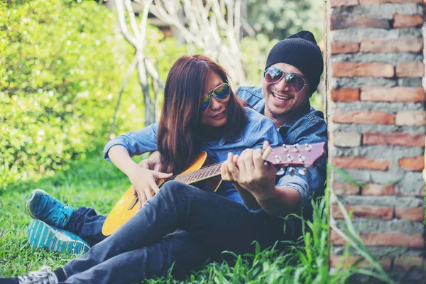 Kız arkadaşı için açık tuğla duvara gitar hipster adam birlikte zevk.