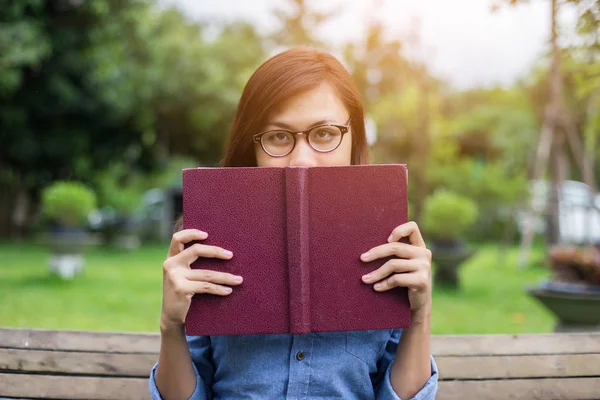 A woman sitting in the garden reading a book.