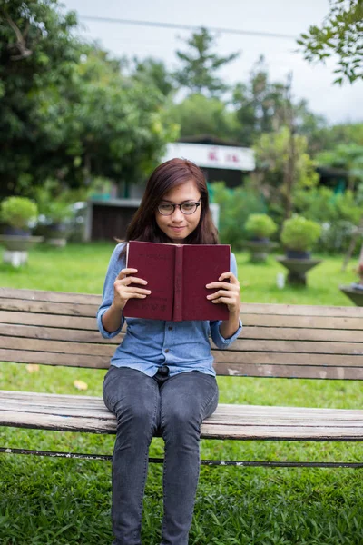 Bir kitap okuma bahçede oturan bir kadın.