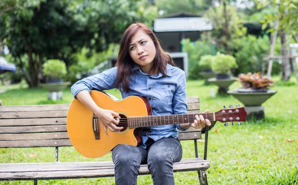 Güzel genç kadın mutlu zaman kavramı banktaoturuyor gitar çalmak.