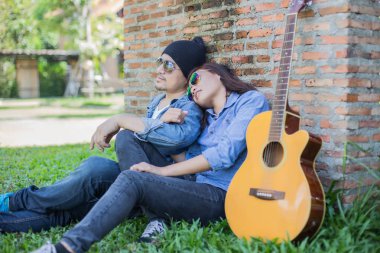 Kız arkadaşı için açık tuğla duvara gitar hipster adam birlikte zevk.