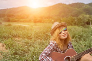 Bir gitar çalıyor ve şarkı oturan genç hippi kız.