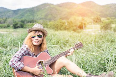 Bir gitar çalıyor ve şarkı oturan genç hippi kız.