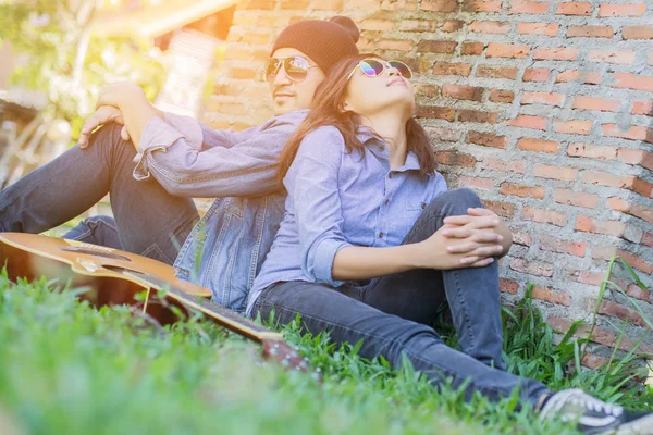 Kız arkadaşı için açık tuğla duvara gitar hipster adam birlikte zevk.