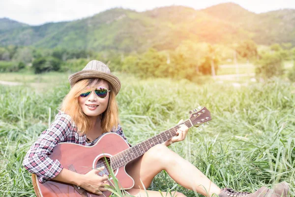Bir gitar çalıyor ve şarkı oturan genç hippi kız.
