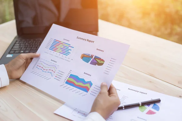 Hands of Businessman working on Laptop Computer with Data Charts