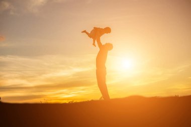 Baba ve küçük kızı günbatımında yürüyüş siluetleri