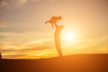 Baba ve küçük kızı günbatımında yürüyüş siluetleri