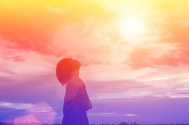 Güzel bir arka plan için dua eden bir kadın silueti.