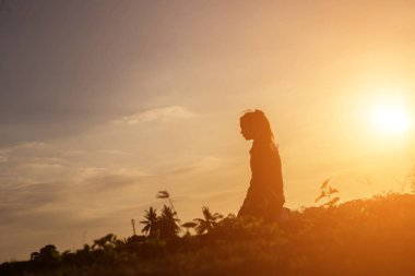 Güzel bir arka plan için dua eden bir kadın silueti.