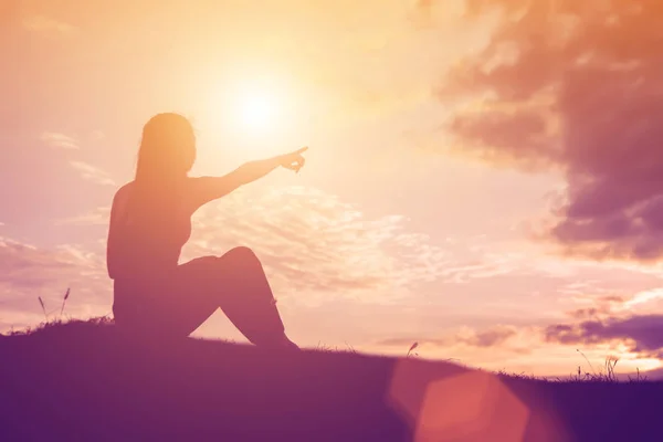 Silhouette of woman praying over beautiful sky background