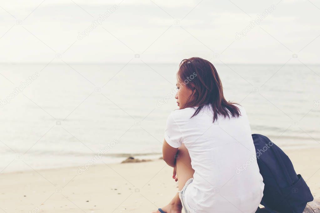 Sad lonely beautiful woman sitting on the pier