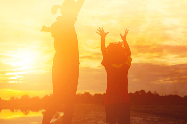 Mother encouraged her daughter out of the shadows at sunset.