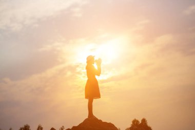 Güzel bir arka plan için dua eden bir kadın silueti.