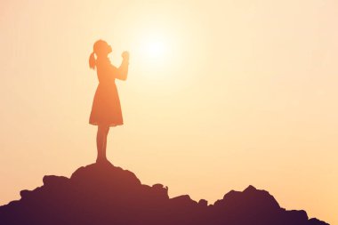 Güzel bir arka plan için dua eden bir kadın silueti.