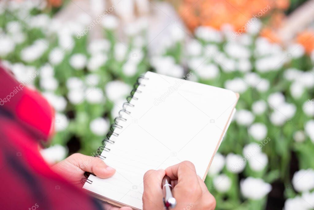 Woman taking notes in a white flower garden