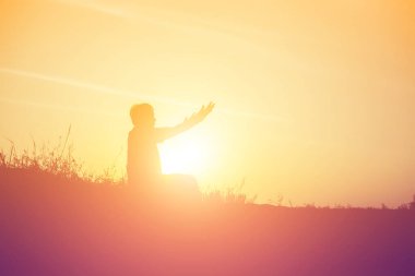 Güzel bir arka plan için dua eden bir kadın silueti.