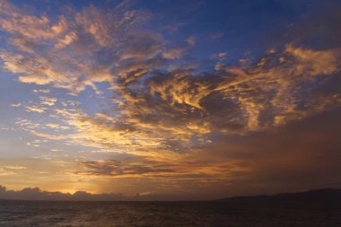 Yaz günbatımı renkli gökyüzü ile pitoresk su manzara üzerinde dramatik mor kırmızı ve sarı bulutlar. Bali, Endonezya.
