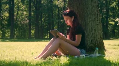 Park kız öğrenci dijital tablet parkta kullanır.