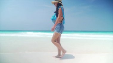 Okyanus boyunca kum plajındaki yalınayak kız yürüyor