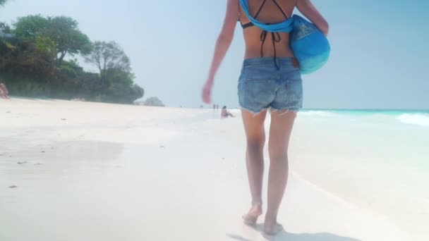 Босоногая девушка ходит по песчаному пляжу вдоль океана — стоковое видео