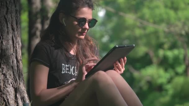 Jeune femme utilise tablette numérique dans le parc — Video