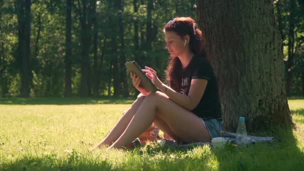 Jonge vrouw in park maakt gebruik van smartphone en tablet — Stockvideo