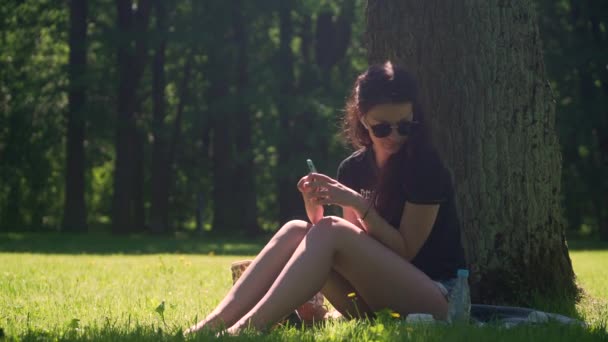 Молодая женщина использует смартфон и пьет воду — стоковое видео