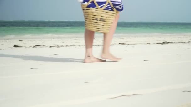Молодая женщина ходит босиком по пляжу вдоль океана — стоковое видео