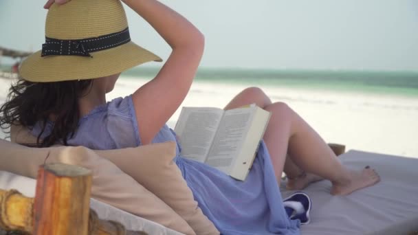 Mujer joven leyendo libro sobre playa blanca por océano . — Vídeo de stock