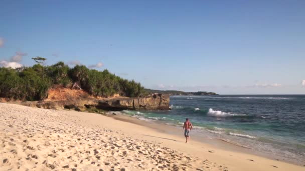 Człowiek biegnie do wody na pięknej plaży w lagunie — Wideo stockowe