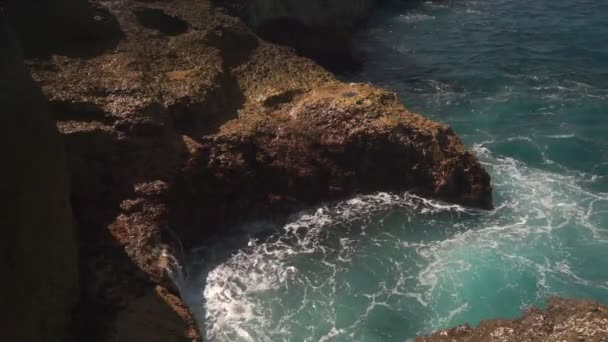 L'acqua dell'oceano si rompe sulle rocce nella luminosa giornata di sole — Video Stock